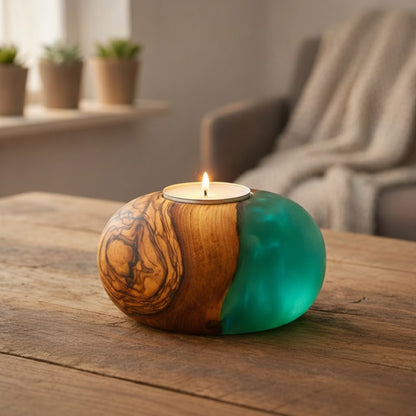 Ronde theelichthouder van olijfhout met turquoise epoxy en brandende kaars op een houten tafel